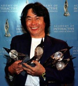 Shigeru Miyamoto holding five of the eleven awards that "The Legend of Zelda: Ocarina of Time" won at the Academy of Interactive Arts and Sciences Achievement Award in Los Angeles (May 13,